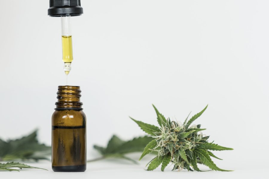 Close-up of hand holding pipette with hemp oil and marijuana bud Close-up of hand holding pipette with hemp oil and marijuana buds. Medicinal extract oil in a bottle. Concept of using cannabis herb and leaves for treatment