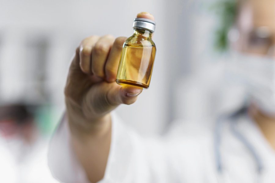 front-view-defocused-female-researcher-with-vaccine-bottle
