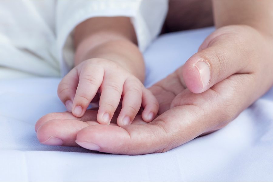 imagem-recortada-de-pai-e-bebe-de-maos-dadas-na-cama-em-casa