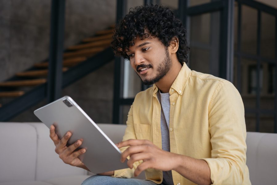 indian-man-reading-ebook-smiling-asian-freelancer-using-digital-tablet-working-online-from-home