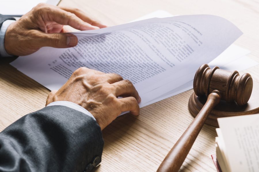 lawyer-s-hand-holding-document-with-gavel-mallet-wooden-desk