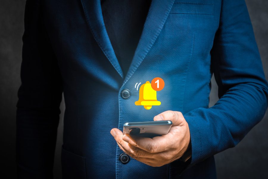 push notification. Businessman holding smartphone with virtual yellow bell ringing for application notification alert concept. Hand of businessman using cellphone for push notification alert