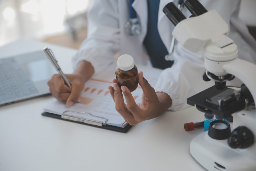 Professional lab. Amazing longhaired medical worker wearing uniform while using microscope during research